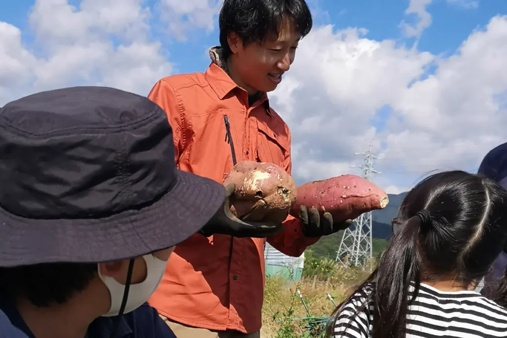 mino-LLのスタッフが利用者の子どもに農作業を指導している様子（豊川市足山田町）